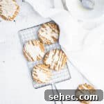 brown butter iced pumpkin cookies on a small silver cooling rack next to a piece of white linen and a bowl.