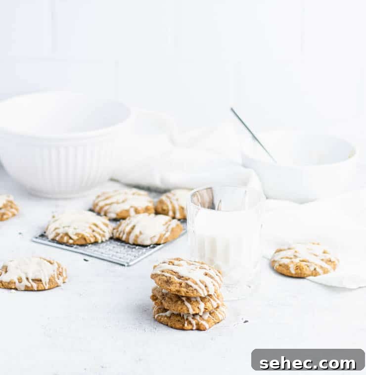 Pumpkin Oatmeal Cookies with Brown Butter Icing 7 Iced pumpkin oatmeal cookies stacked in front of a cooling rack of cookies, and white bowls.
