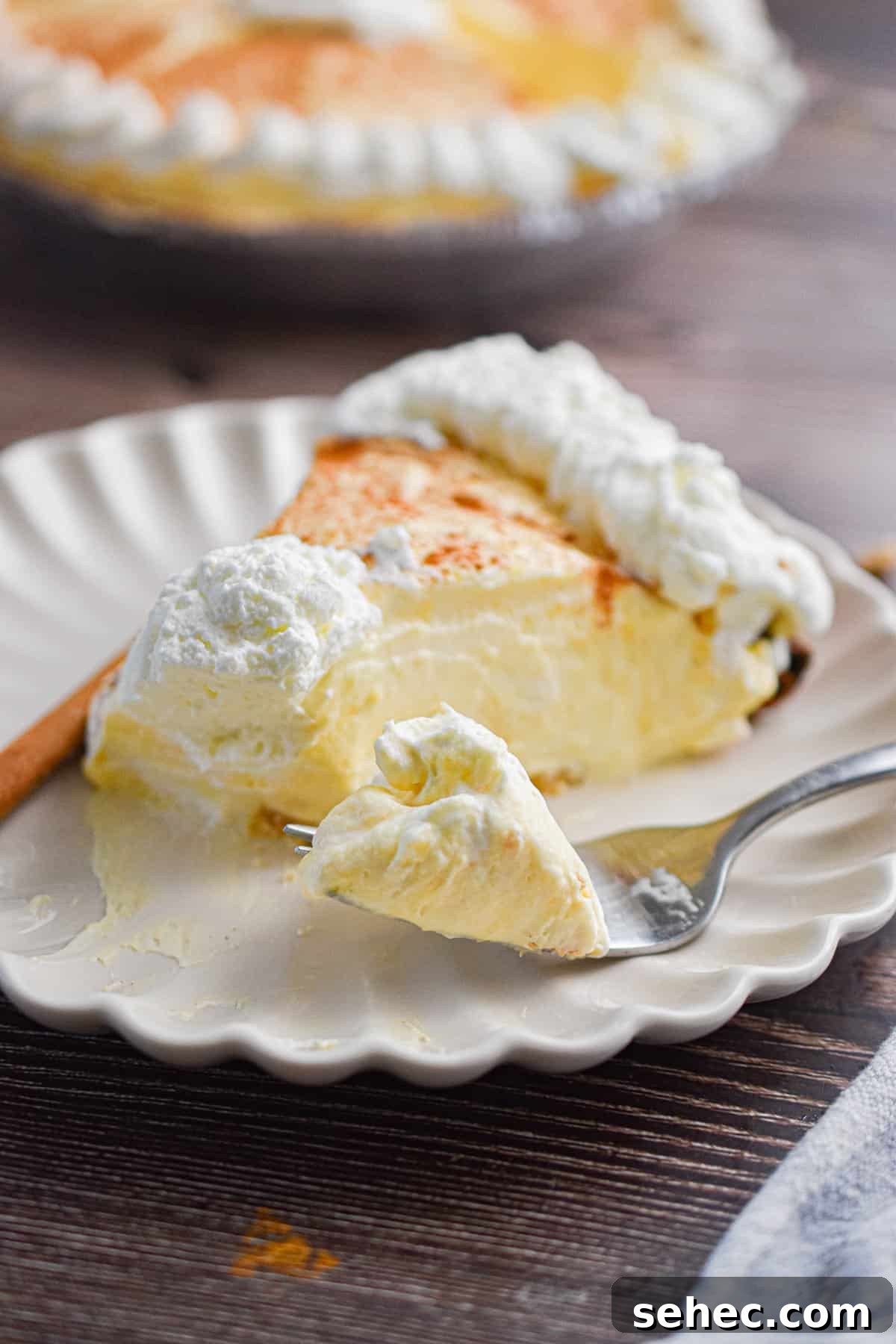 Eggnog Cream Pie Recipe for the Holidays 10 A piece of the no-bake eggnog pie is on a plate with a fork holding a piece of that pie.