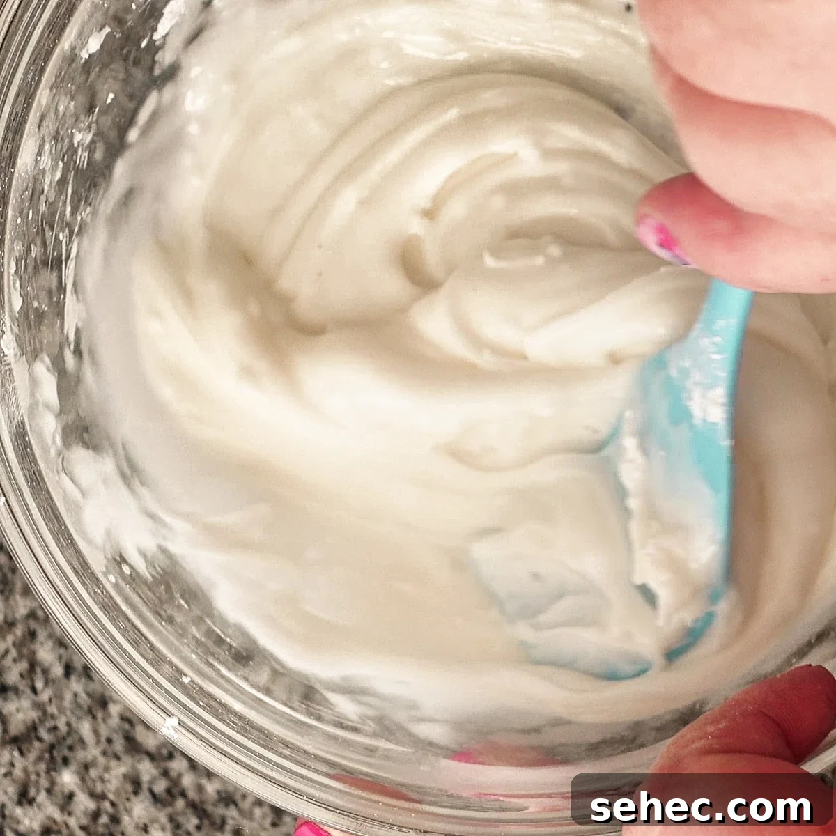 Gluten Free King Cake Recipe for Mardi Gras 15 Mixing white icing in glass bowl with a blue spatula.