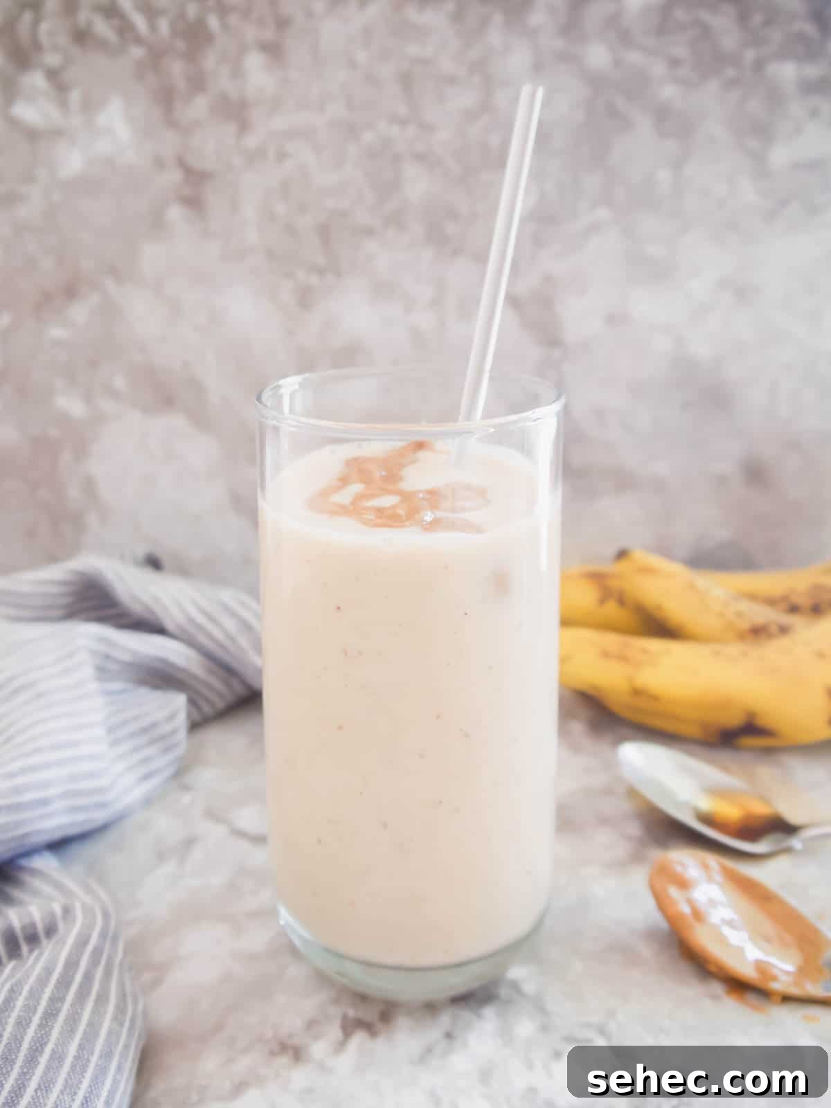 Maple Banana Yogurt Smoothie 2 A banana yogurt smoothie with maple syrup in a tall glass with a straw.
