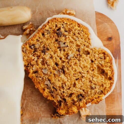 A slice of pumpkin walnut bread on a wooden cutting board.