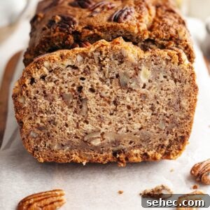 One Bowl Brown Butter Cinnamon Banana Bread with Pecans 17 Close-up of a slice of pecan banana bread on parchment paper.