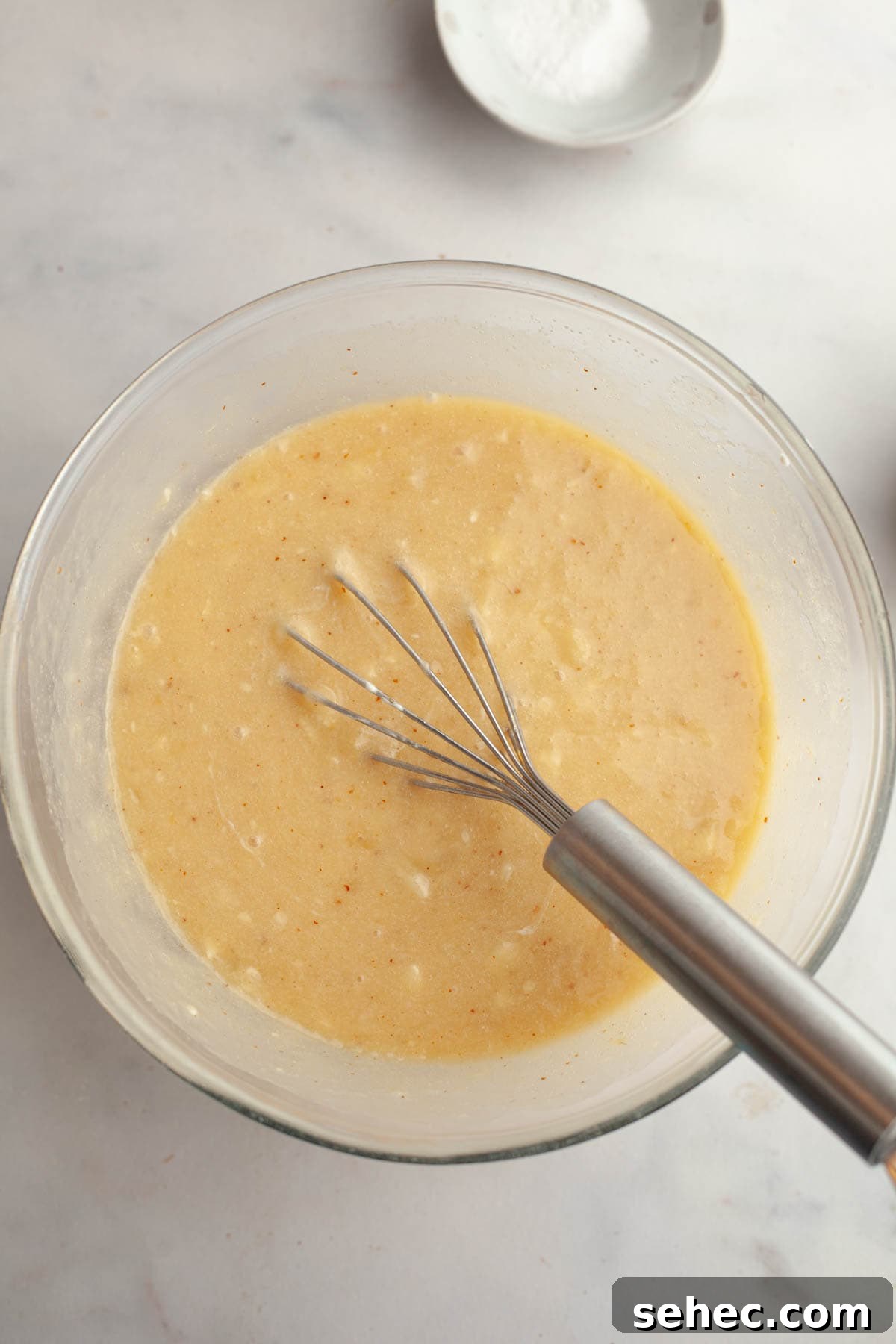 One Bowl Brown Butter Cinnamon Banana Bread with Pecans 5 Banana bread batter in a large glass mixing bowl with a whisk.