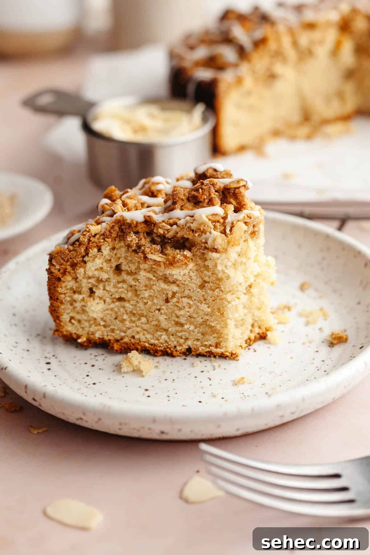 Brown Butter Cardamom Almond Cake Recipe 11 A slice of almond cardamom cake on a plate, a bite has been taken out of it.
