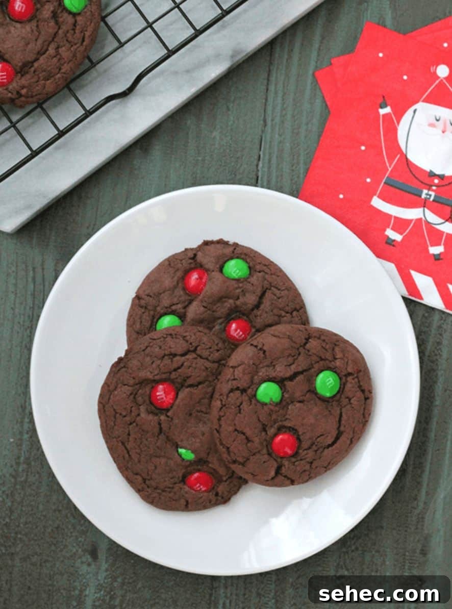 19 Big Batch Cookie Recipes for Parties and Crowds 13 Chocolate cookies with red and green M&Ms on a plate, with a Christmas napkin and cooling rack.