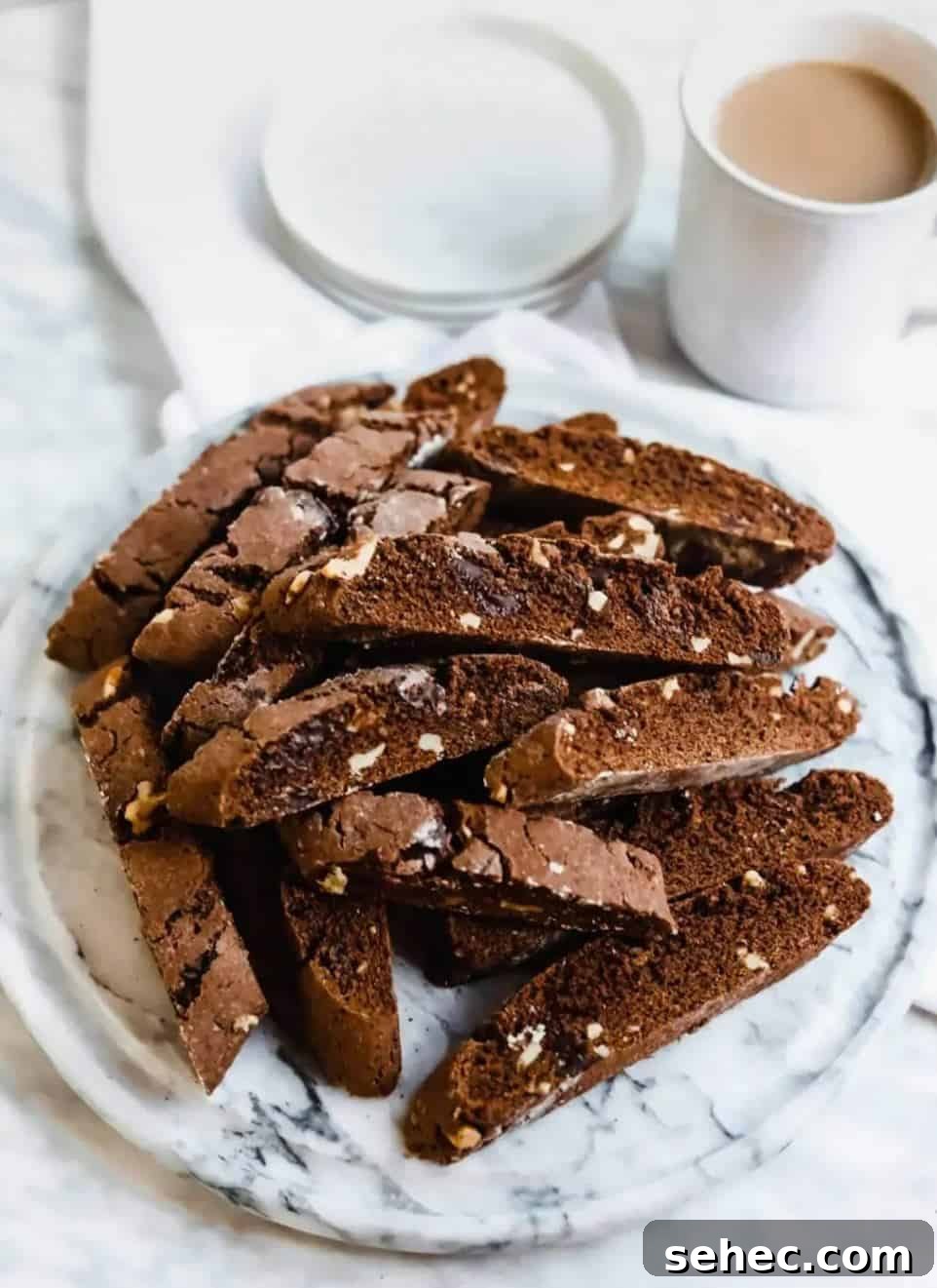 19 Big Batch Cookie Recipes for Parties and Crowds 4 Chocolate biscotti cookies on a plate with a cup of coffee.