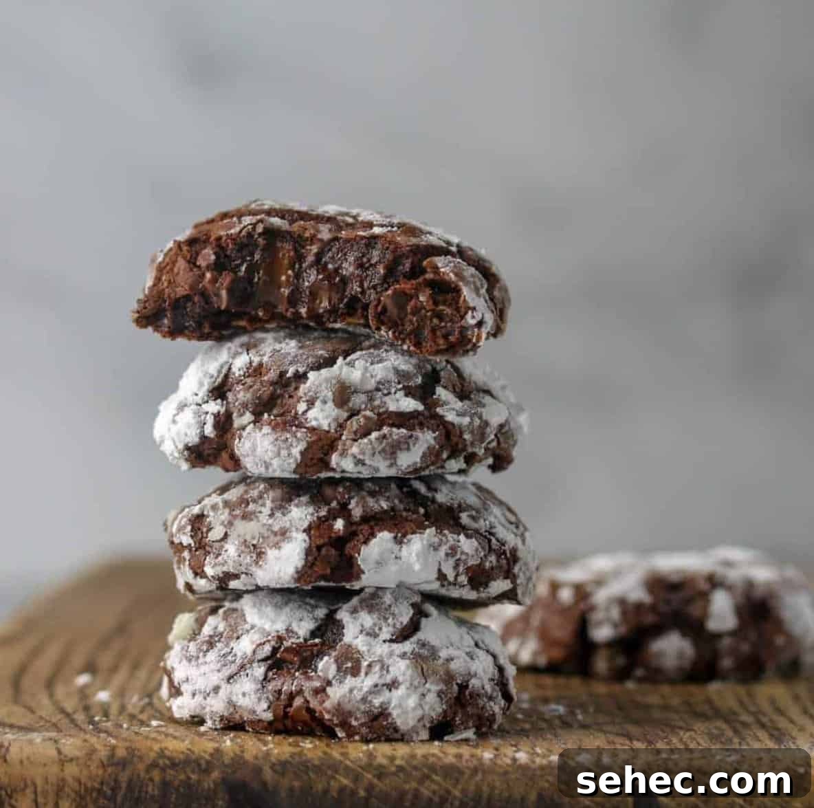 19 Big Batch Cookie Recipes for Parties and Crowds 8 Chocolate cookies with frosting stack on top of each other on a wooden cutting board.