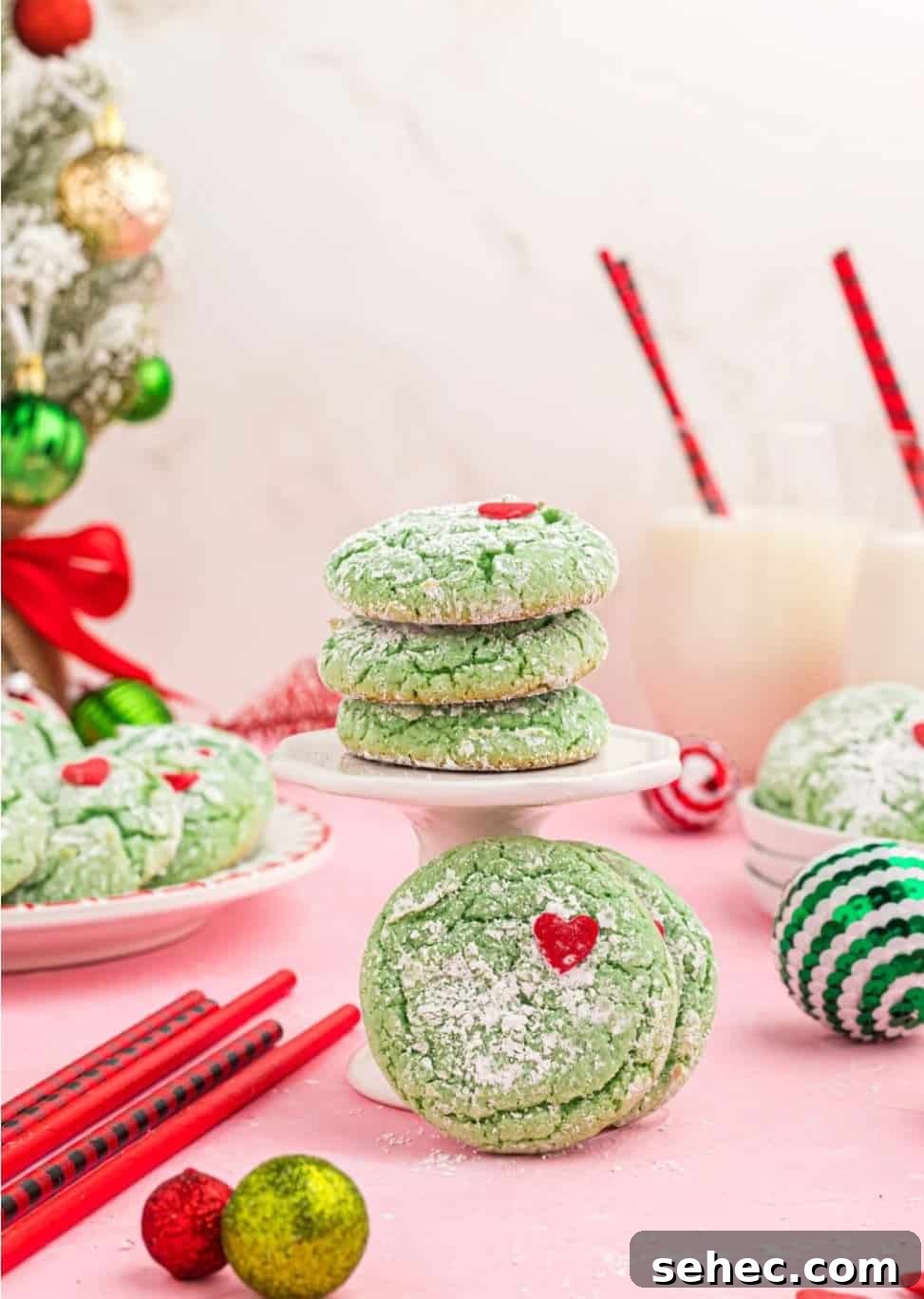 19 Big Batch Cookie Recipes for Parties and Crowds 10 Green cookies with red hearts stacked on plates with Christmas decorations.