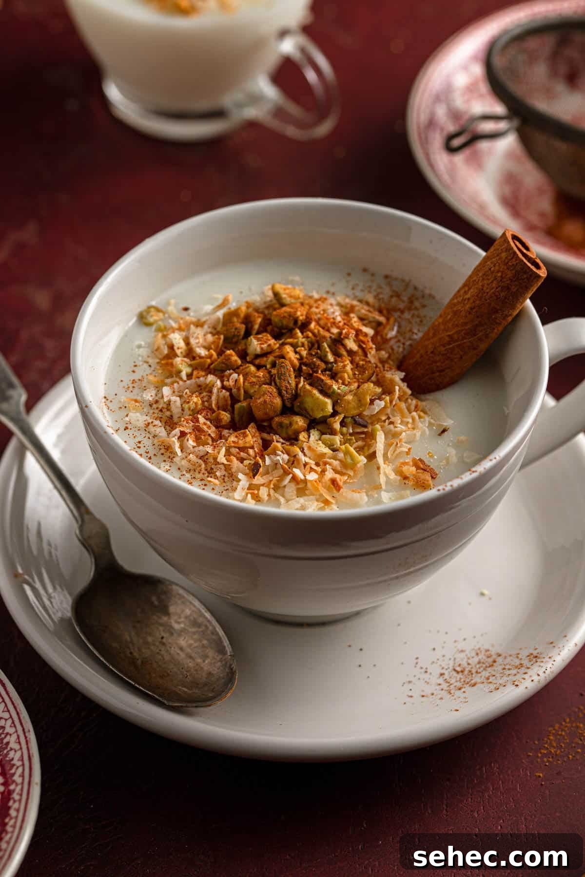 Creamy Sahlab Recipe for a Cozy Middle Eastern Drink 2 A mug filled with warm milk pudding and topped with shredded coconut, chopped pistachios and cinnamon.