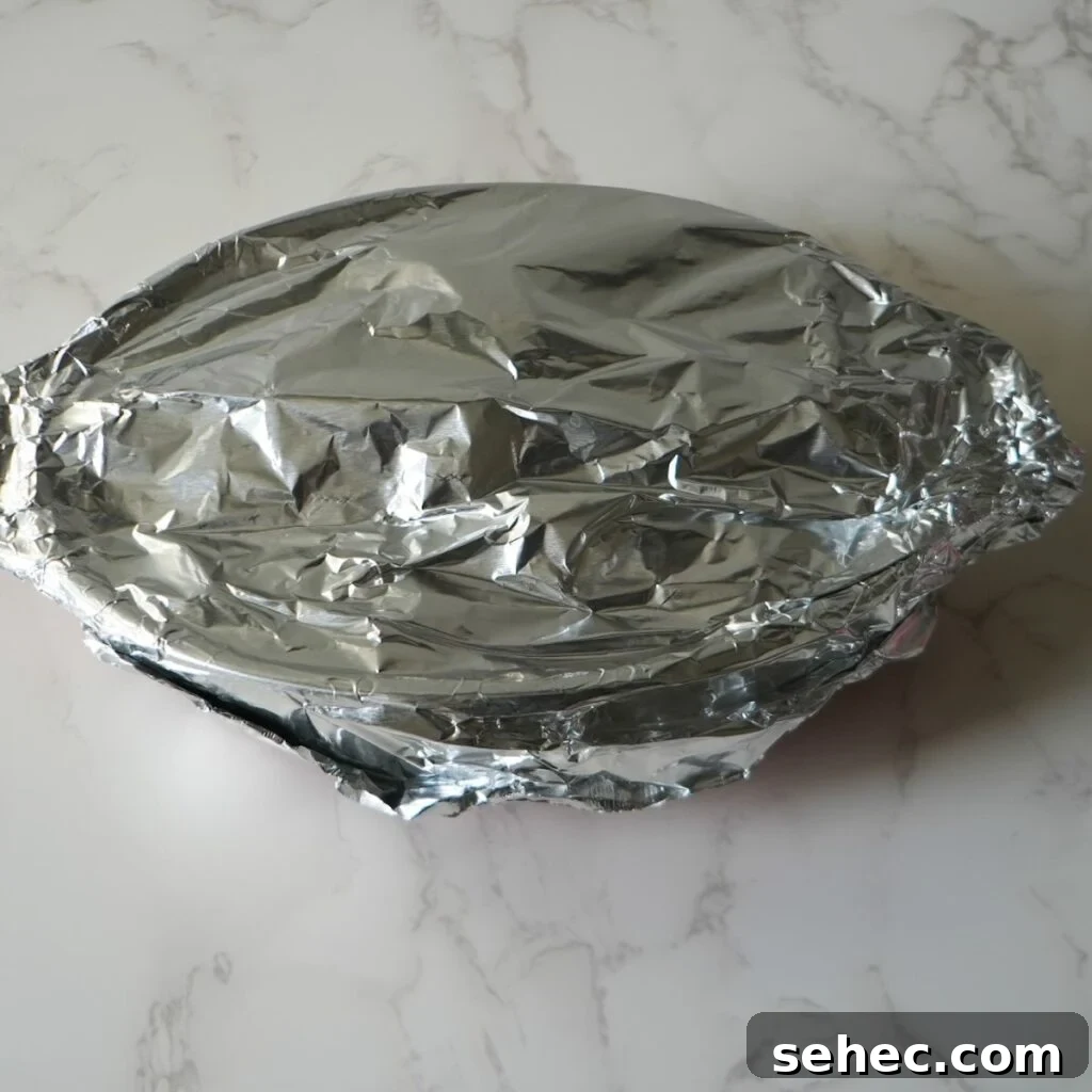 Southern Candied Yams with Brown Sugar and Butter 7 Foil wrapped over a baking dish.