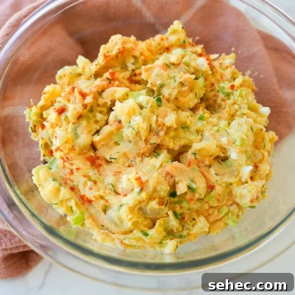 Southern Candied Yams with Brown Sugar and Butter 9 Creamy potato salad in a bowl with chopped eggs, herbs, celery, and smoked paprika on top.