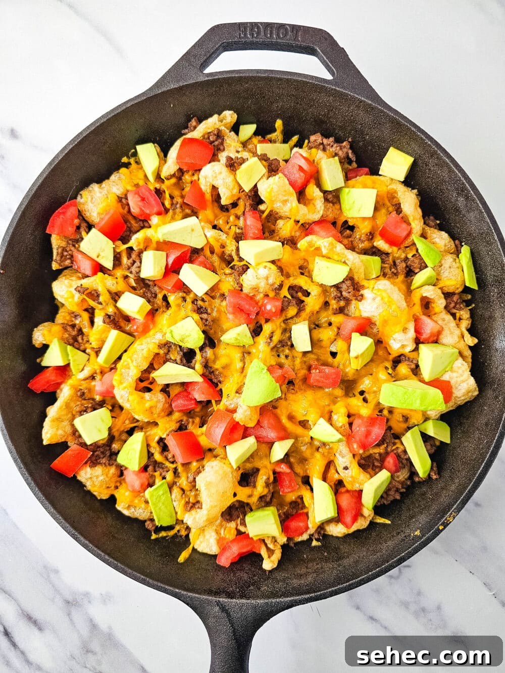 Cast Iron Skillet Pork Rind Nachos 12 Pork rind nachos with tomatoes and avocado in a cast iron skillet