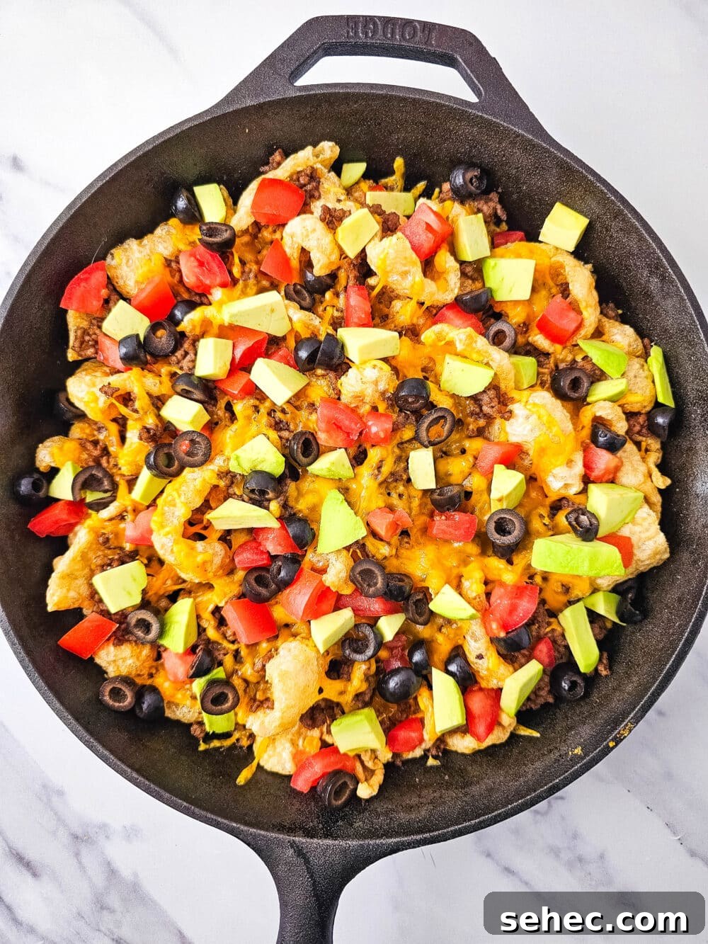 Cast Iron Skillet Pork Rind Nachos 13 Pork rind nachos with tomatoes, avocado, and black olives in a cast iron skillet