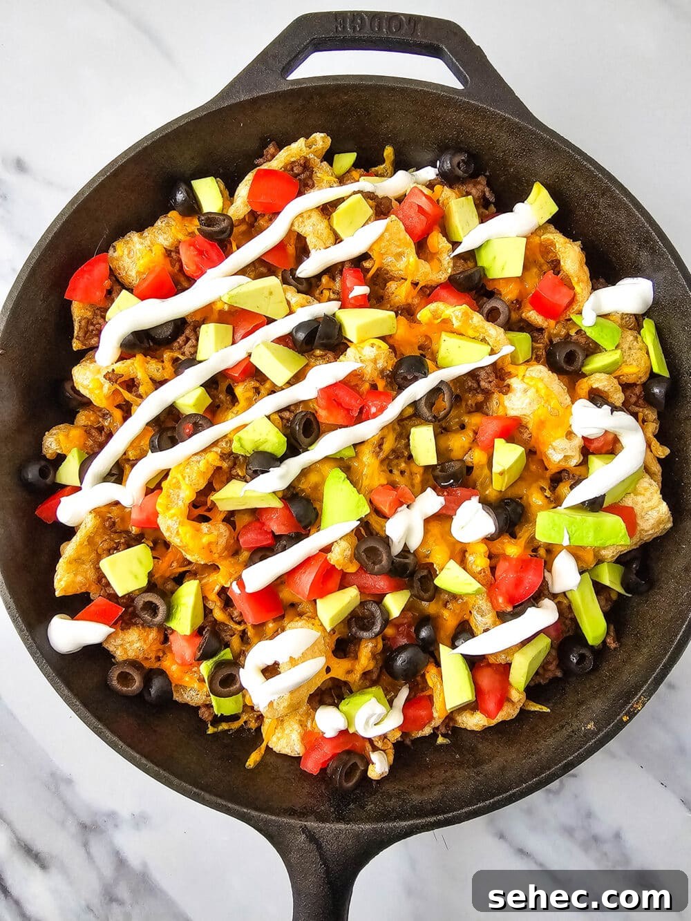 Cast Iron Skillet Pork Rind Nachos 14 Pork rind nachos with tomatoes, avocado, olives, and sour cream in a cast iron skillet