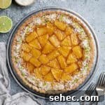 Vegan Caramelized Pineapple Coconut Tart 18 Caramelised pineapple coconut tart on a metal plate with forks, sliced limes and a bowl of desiccated coconut.