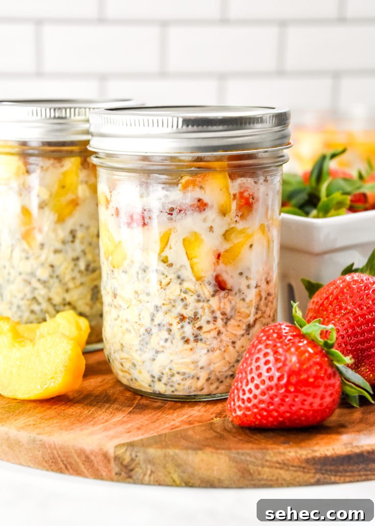 mason jar full of strawberry peach overnight oats on a cutting board.