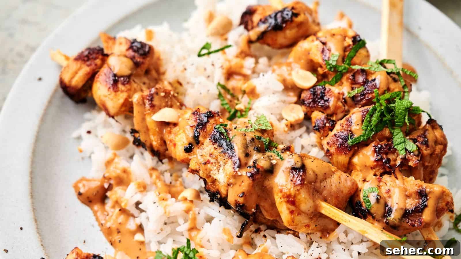 17 Budget Cookout Recipes That Save Room for Better Burgers 11 Thai chicken skewers topped with a creamy sauce and garnished with chopped herbs and peanuts, served over a bed of white rice.