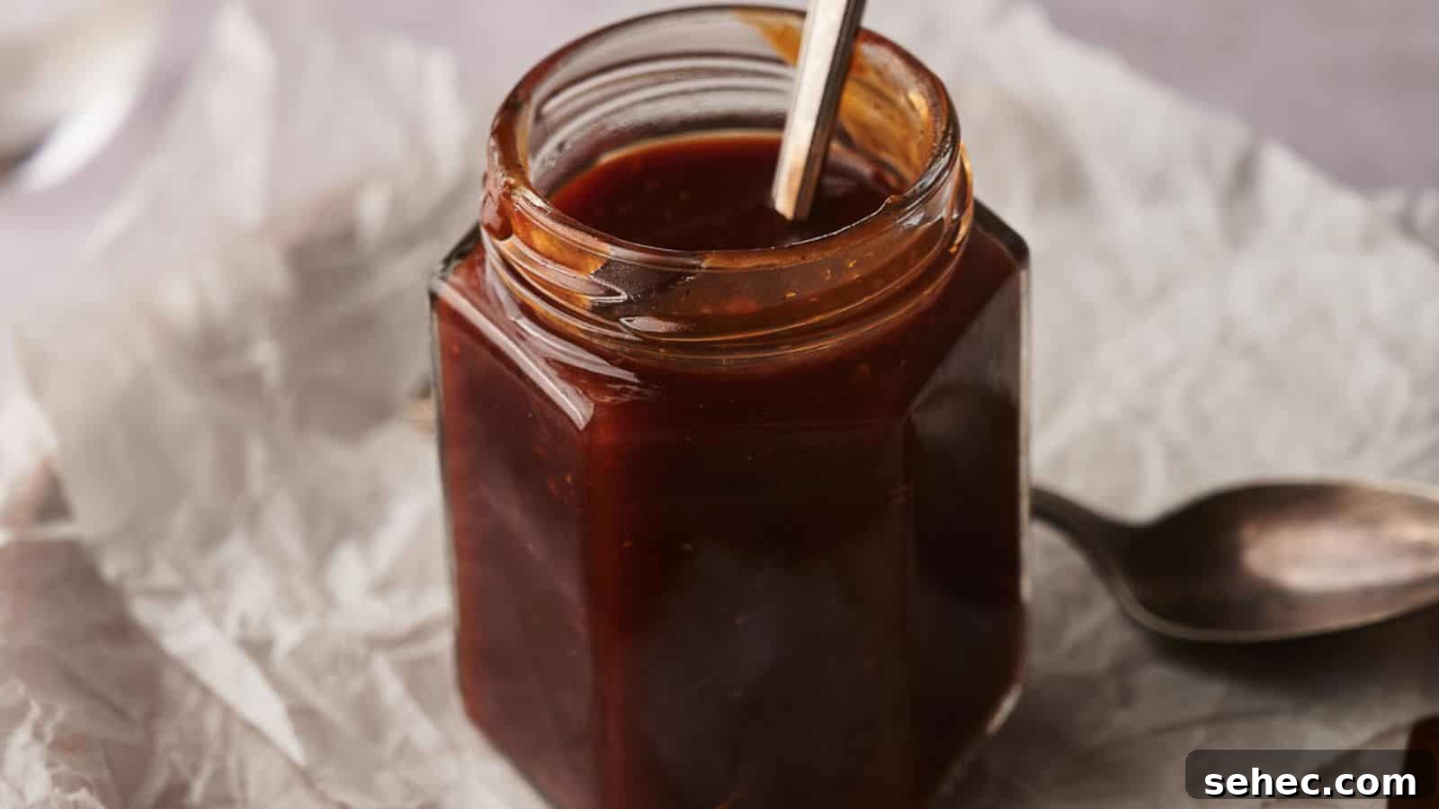 17 Budget Cookout Recipes That Save Room for Better Burgers 15 Homemade BBQ sauce in a jar with two spoons by the side.