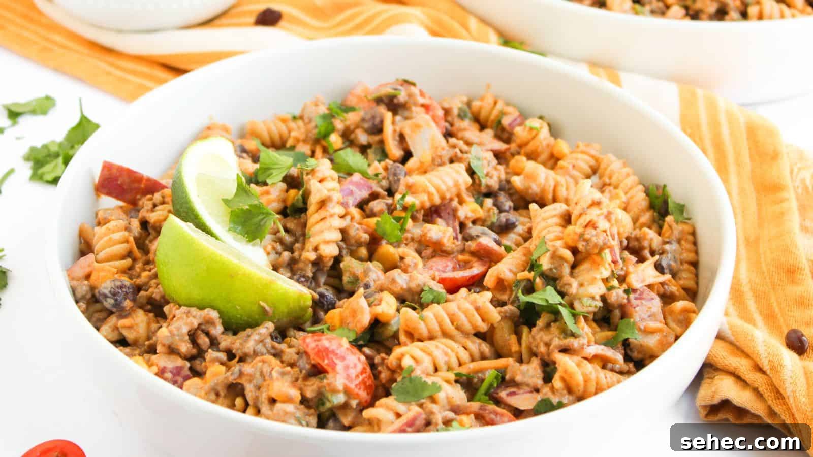 17 Budget Cookout Recipes That Save Room for Better Burgers 18 A bowl of fusilli pasta mixed with ground beef, black beans, chopped tomatoes, and herbs, garnished with lime wedges.