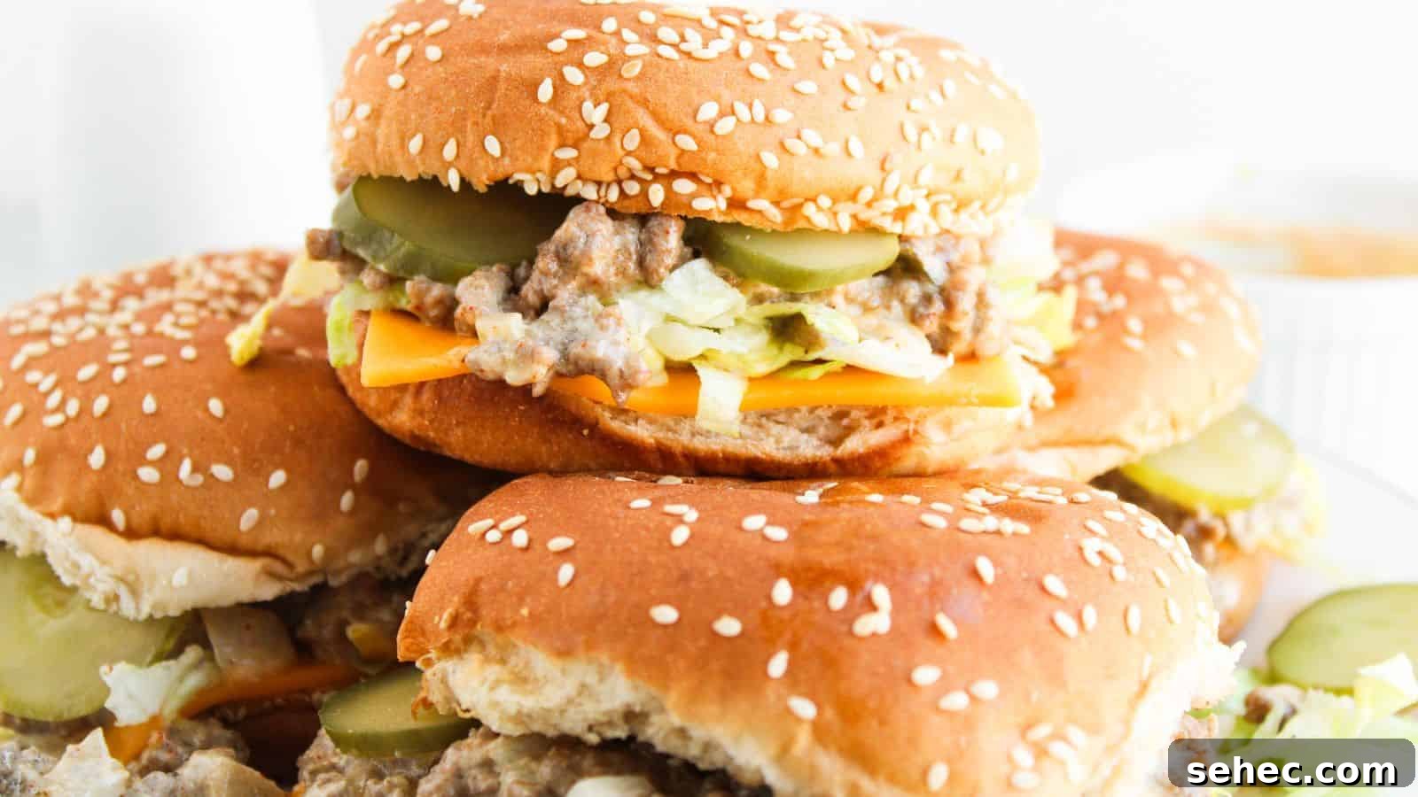 17 Budget Cookout Recipes That Save Room for Better Burgers 8 Two sesame seed burgers with cheese, shredded lettuce, ground meat, and pickles, stacked on a plate.