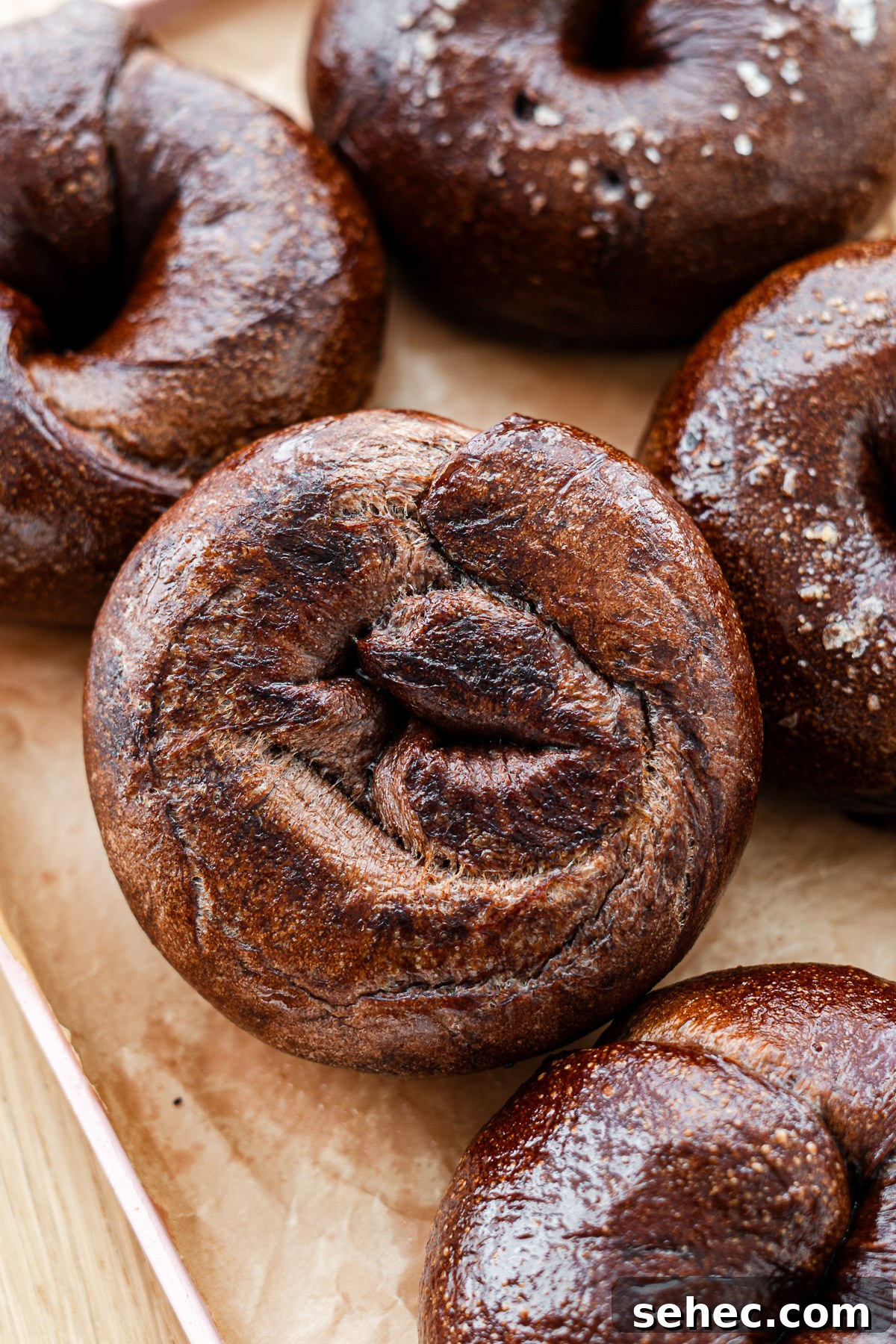 Homemade Chocolate Bagels with Rich Cocoa Flavor 3 crispy bottom of salt bread chocolate bagel on parchment paper on a pink tray