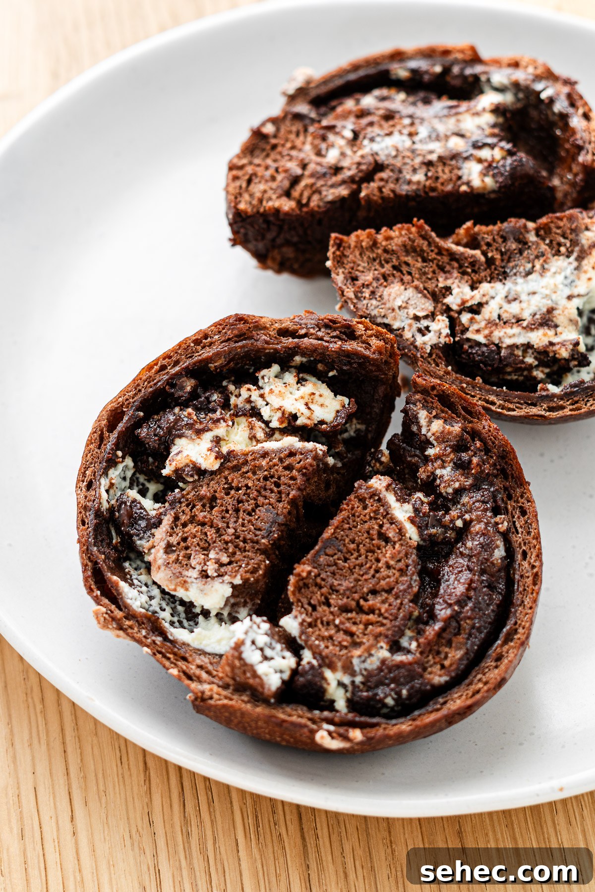 Homemade Chocolate Bagels with Rich Cocoa Flavor 6 cream cheese and chocolate chip stuffed chocolate bagel sliced in half on a white plate