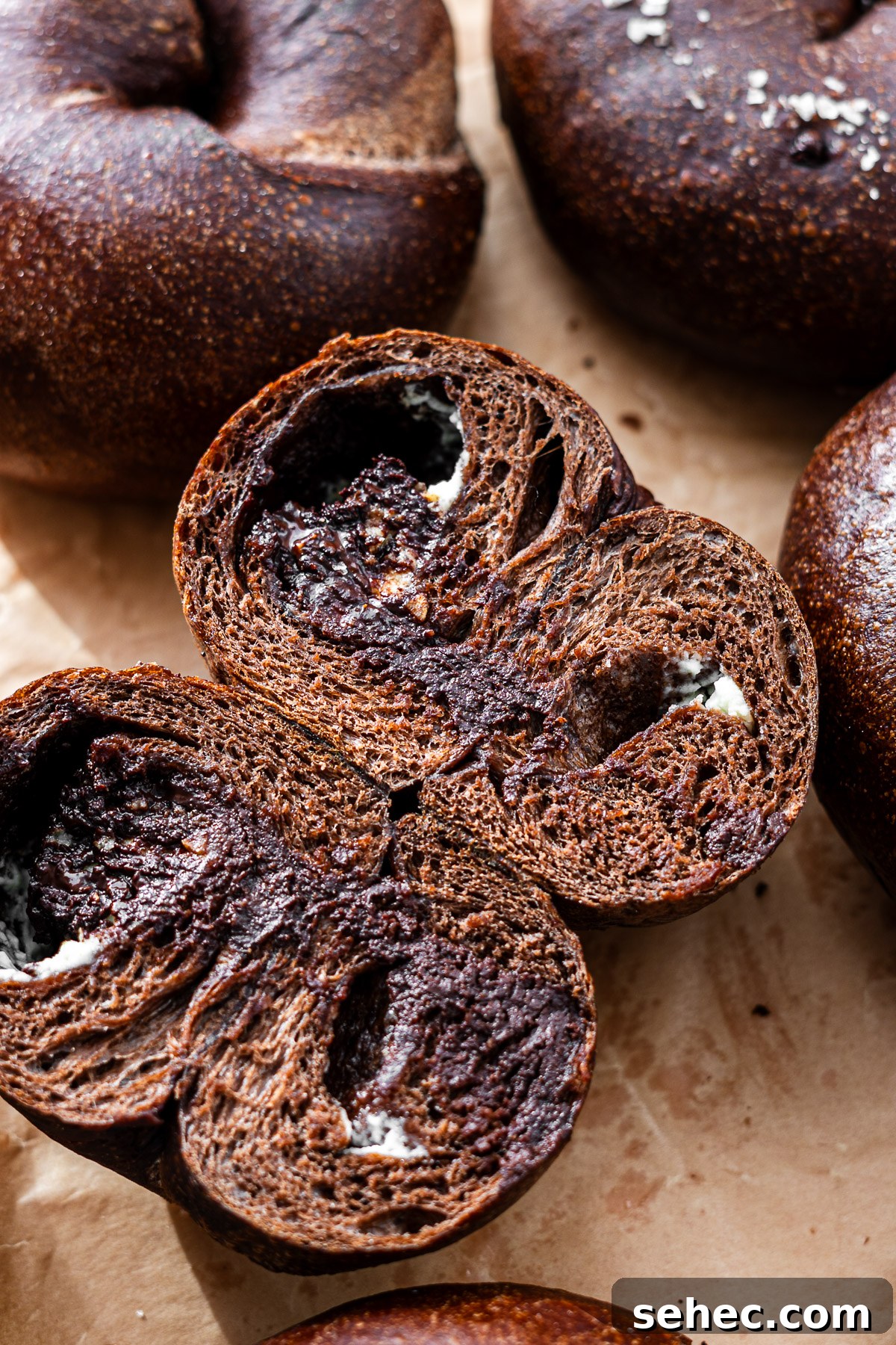 Homemade Chocolate Bagels with Rich Cocoa Flavor 8 cream cheese chocolate stuffed bagel sliced in half on a parchment lined tray
