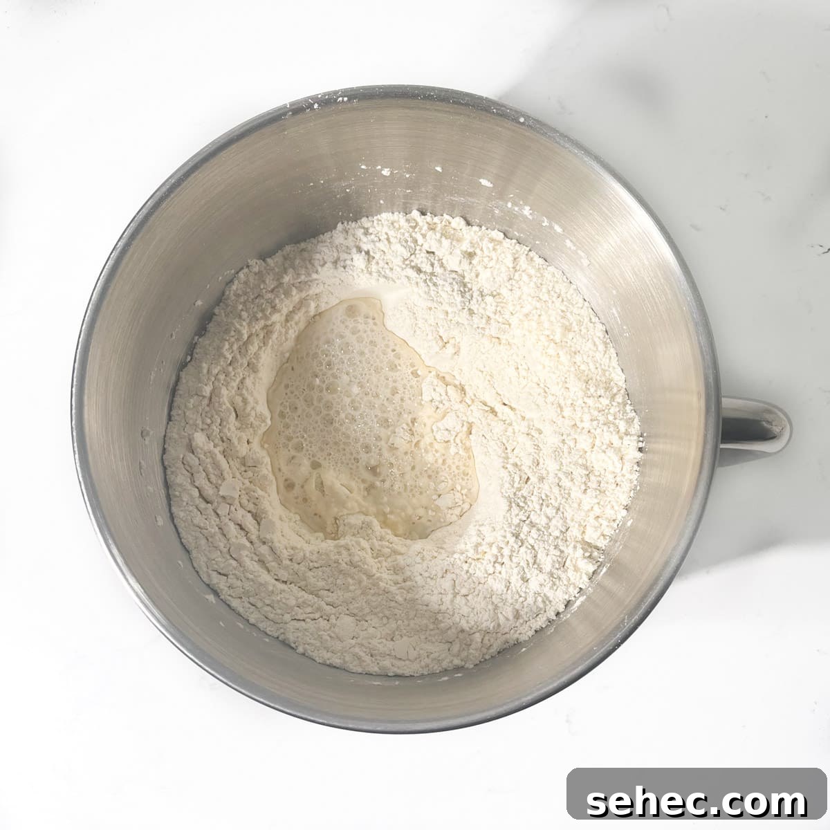 How to Make Authentic South African Vetkoek 7 Adding water to dry ingredients in a large mixing bowl.