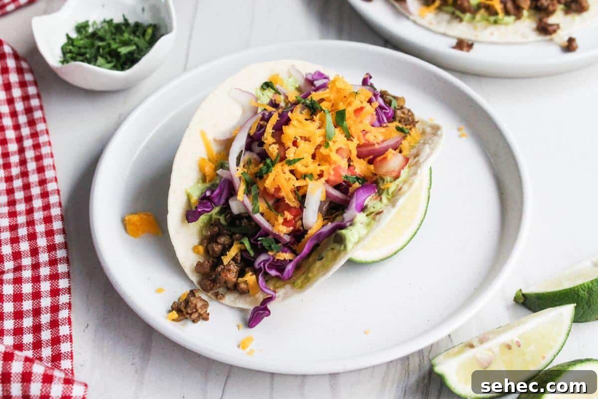19 Weeknight Dinner Recipes You’ll Want to Cook Again 11 Two pork tacos on a white plate with lime wedges.
