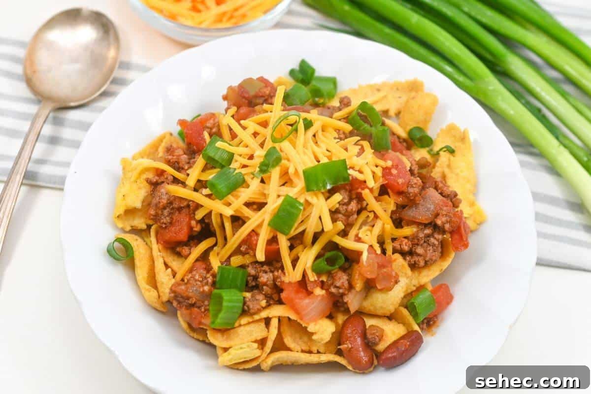 19 Weeknight Dinner Recipes You’ll Want to Cook Again 16 A plate of Fritos topped with ground beef, cheese, tomatoes, beans, and green onions.
