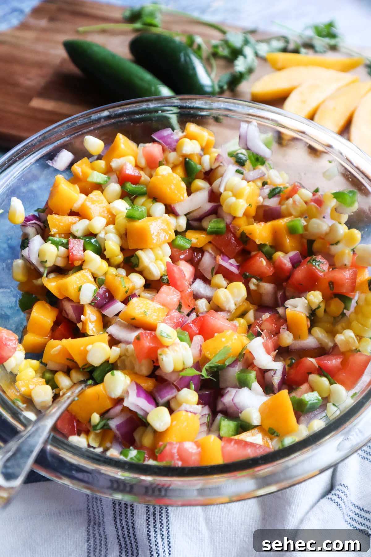 glass bowl with corn mango salsa with red onion, tomatoes, jalapeño, cilantro and more.