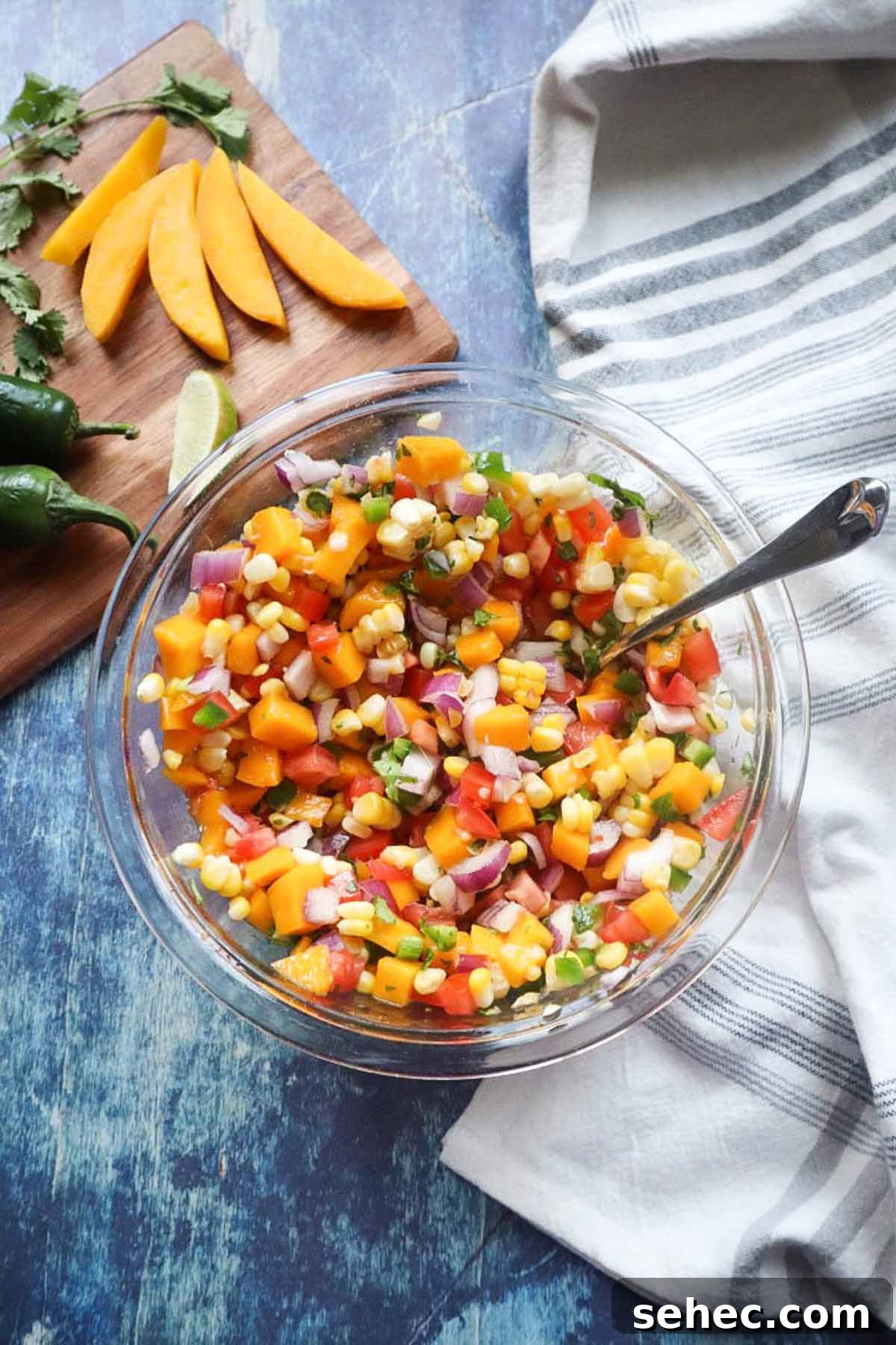 glass bowl with corn mango salsa with red onion, tomatoes, jalapeño, cilantro and more.