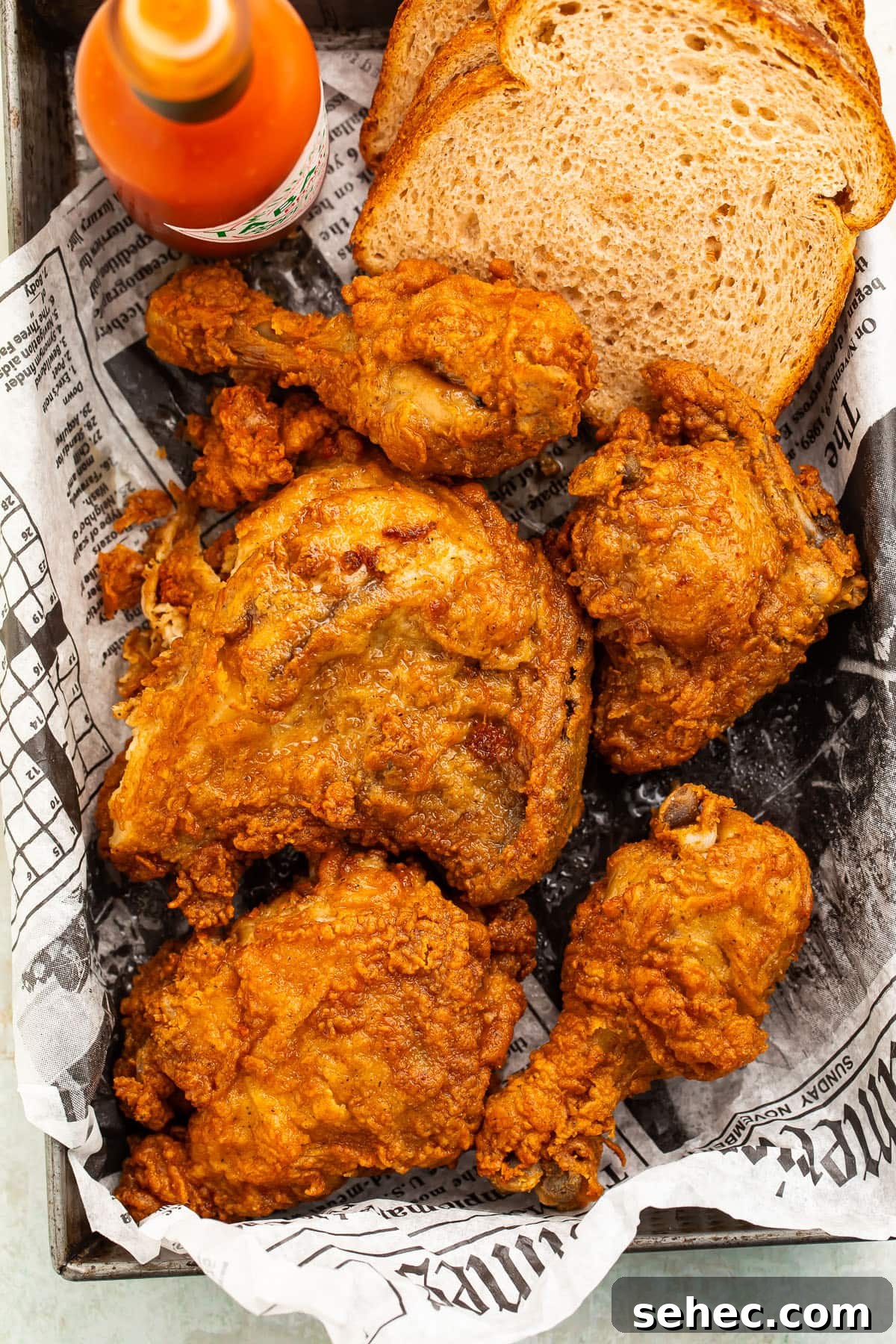 How to Reheat Fried Chicken in an Air Fryer 3 Crispy fried chicken, reheated in the air fryer, in a pan lined with newspaper.