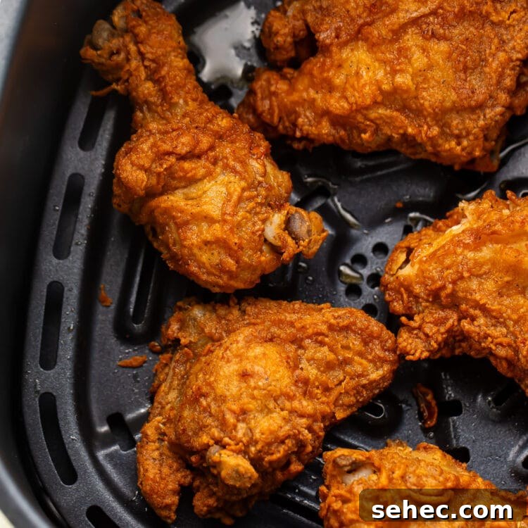 How to Reheat Fried Chicken in an Air Fryer 4 Crispy reheated fried chicken legs, thighs, and breasts in an air fryer basket.