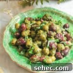 Pesto marinated olives on a small green plate with skewers on the side.