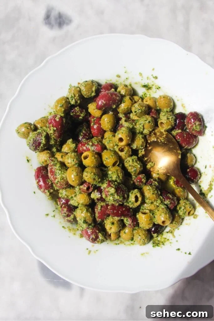 Pesto Marinated Olives Recipe 5 Pesto mixed through olives in a white bowl.