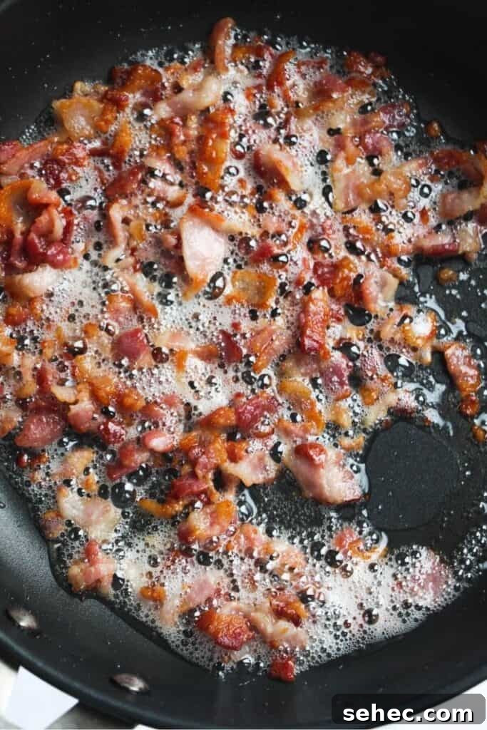 Crispy Smashed Potato Salad with Tzatziki Sauce 8 Bacon pieces cooking in a pan.