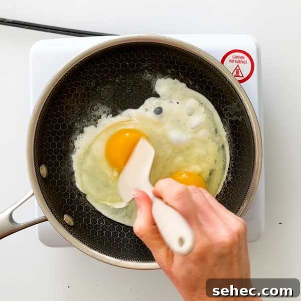 High Protein Loaded Baked Sweet Potato Breakfast 11 Stirring eggs with salt in a skillet.