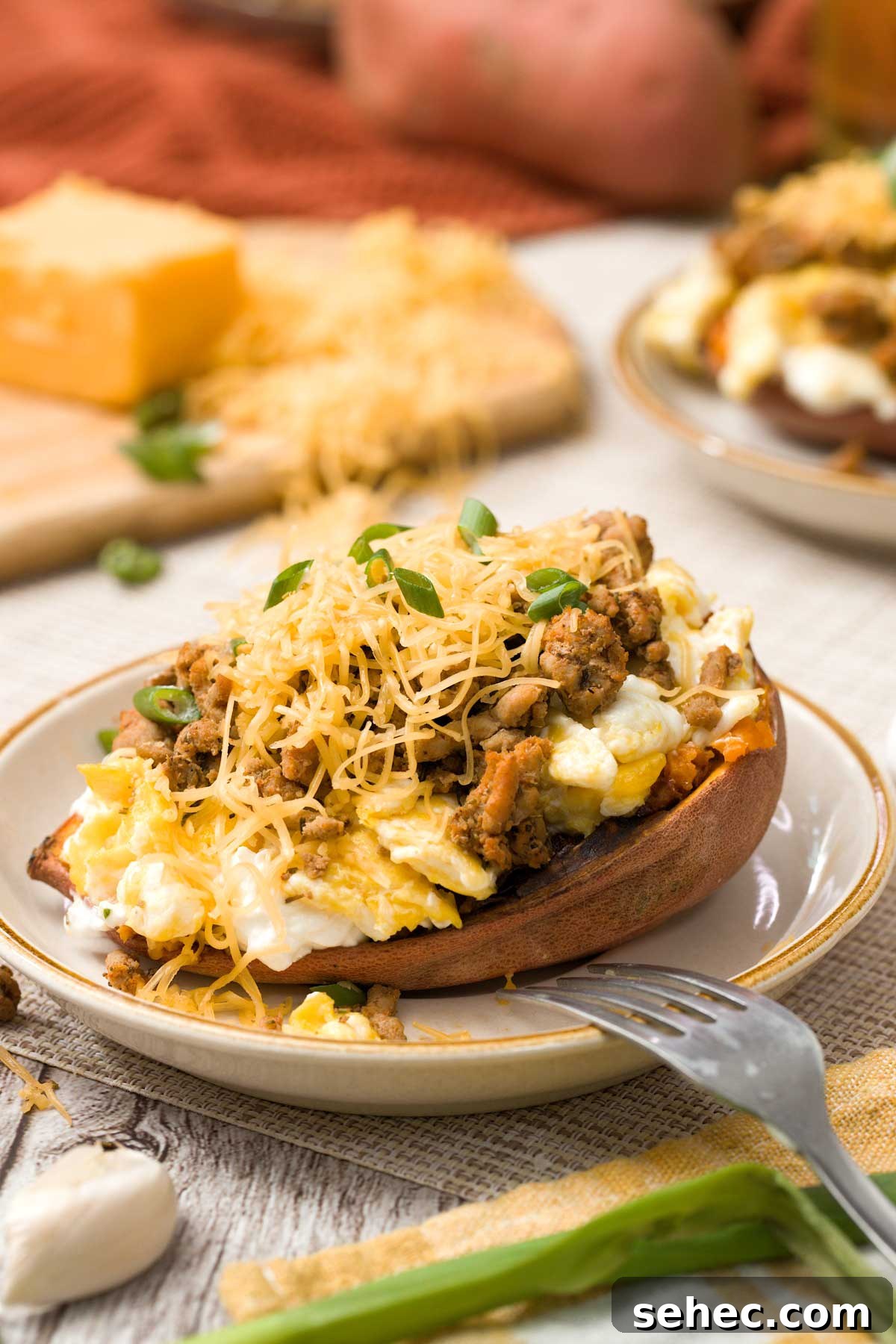 High Protein Loaded Baked Sweet Potato Breakfast 4 Close-up of a loaded sweet potato with shredded cheese and chives on top.
