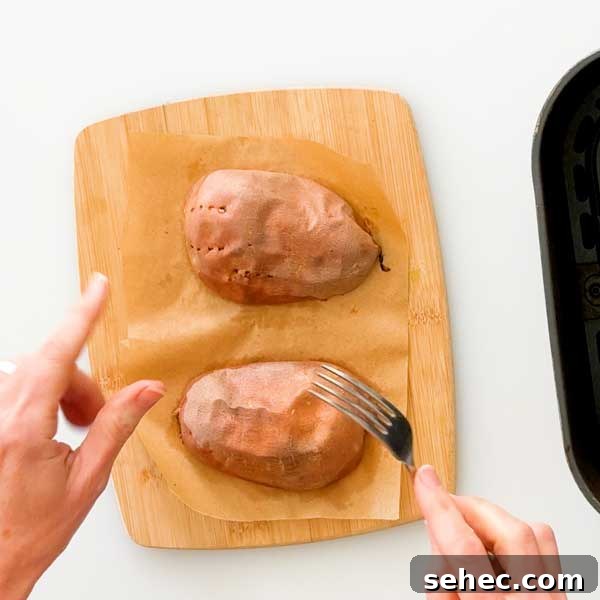 High Protein Loaded Baked Sweet Potato Breakfast 8 Testing baked sweet potatoes with a fork.