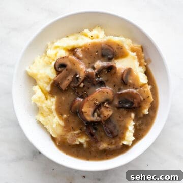 Vegan Mushroom Gravy Recipe 11 Platter featuring vegan mashed potatoes and vegan mushroom gravy against a white backdrop.