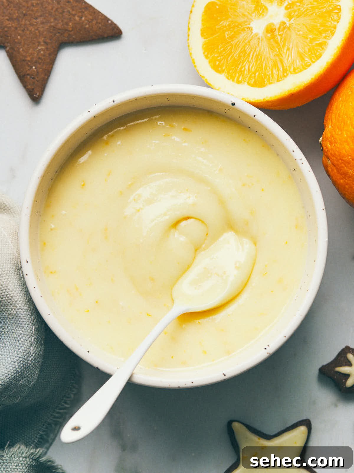 Bowl of icing with orange and gingerbread on table