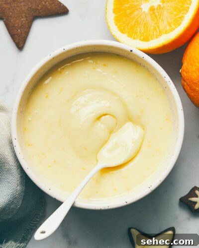 Bowl of icing with orange and gingerbread on table