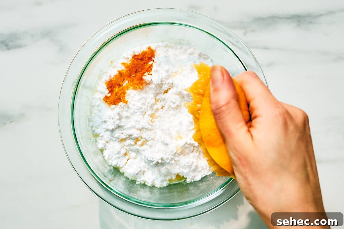 Powdered sugar, orange zest, and orange juice being added to a bowl.