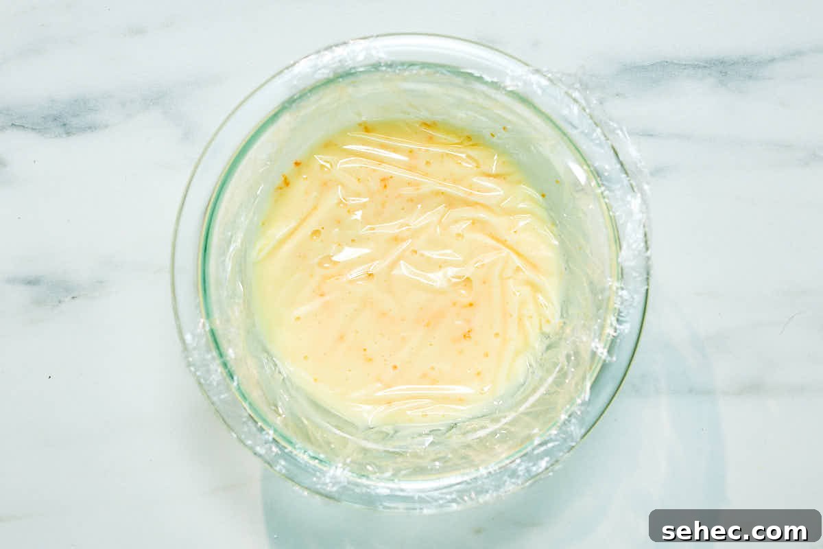 Plastic wrap pressed on top of icing in a bowl to stop icing from hardening.