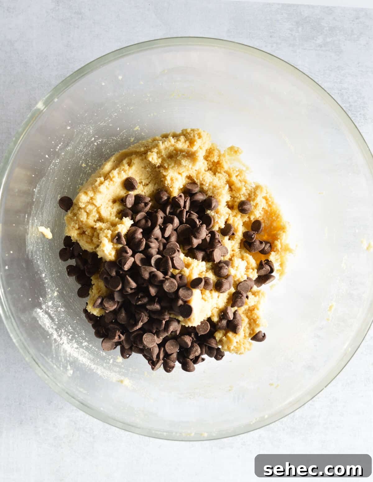 Chewy Almond Flour Chocolate Chip Cookies 10 a bowl of almond flour cookie dough with chocolate chips on top.
