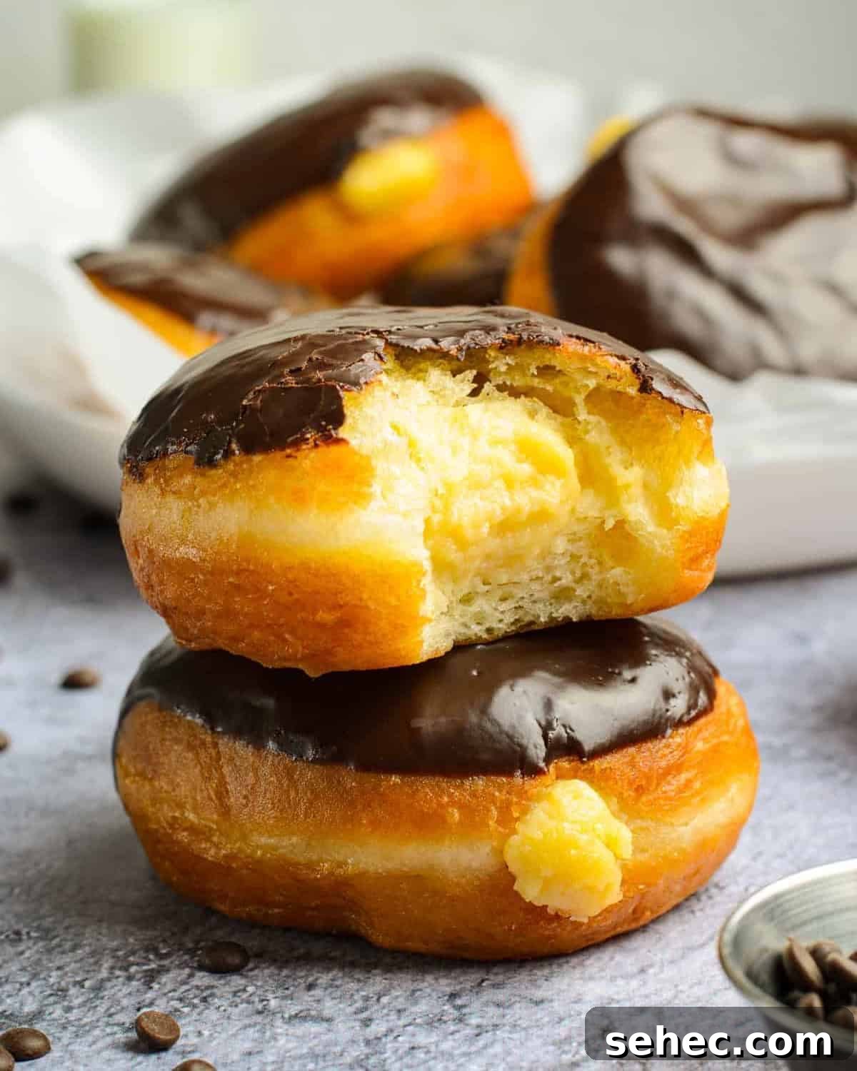 Boston Cream Pie Donuts with Chocolate Glaze 2 a bitten boston cream donut stacked on a whole donut.