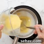 Boston Cream Pie Donuts with Chocolate Glaze 16 pouring tempered eggs into cream in a saucepan.