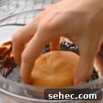 Boston Cream Pie Donuts with Chocolate Glaze 24 dipping a boston cream filled donut in chocolate glaze.